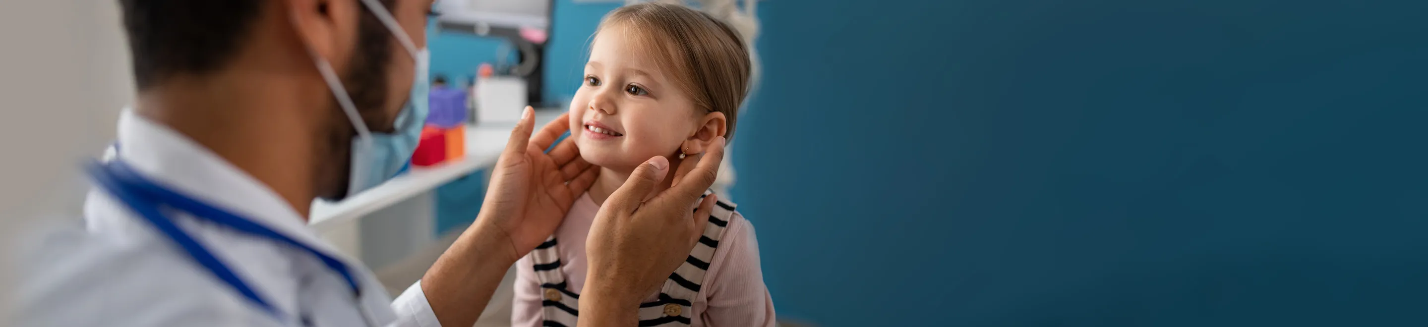 Ein Arzt untersucht ein KLeinkind am Hals.