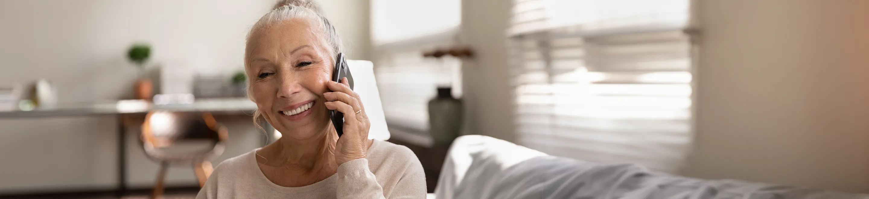 Eine Frau im mittleren Alter telefoniert lächelnd.