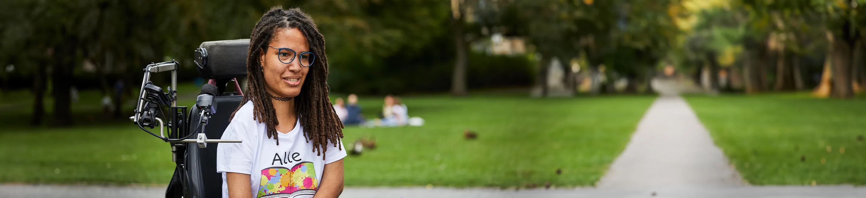 Eine junge Frau im Rollstuhl in einem Park.