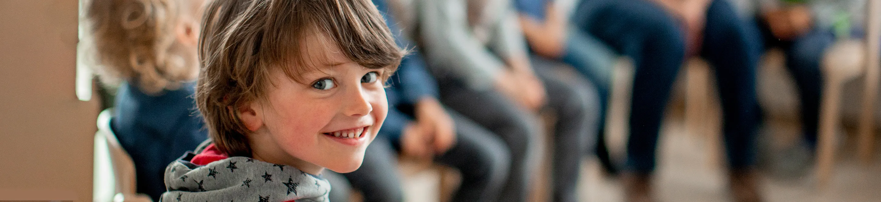 Ein Kleinkind lächelt, im Hintergrund sind noch andere Kinder zu sehen