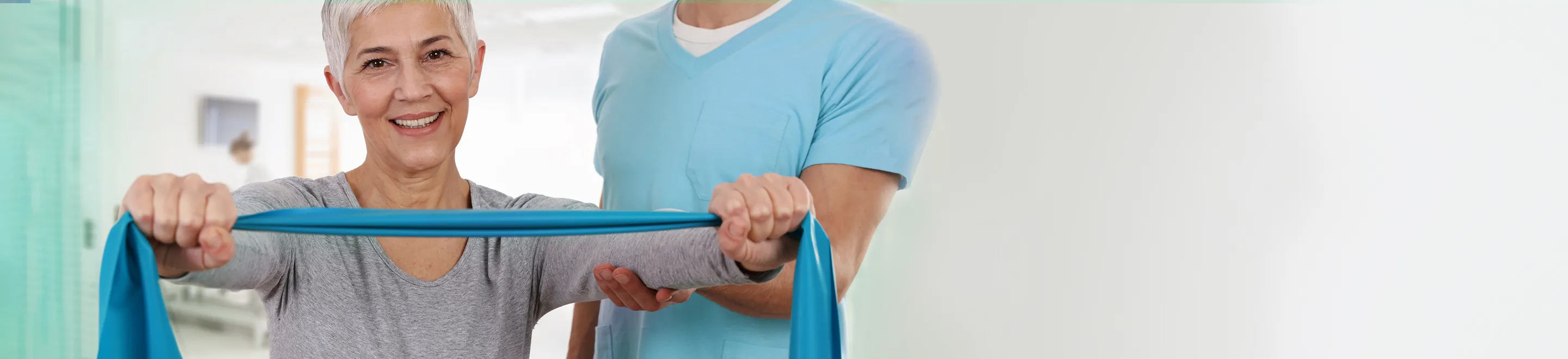 Eine Frau zieht mit beiden Händen an einem blauen Gummiband. Die Übung ist Teil einer Physiotherapie.