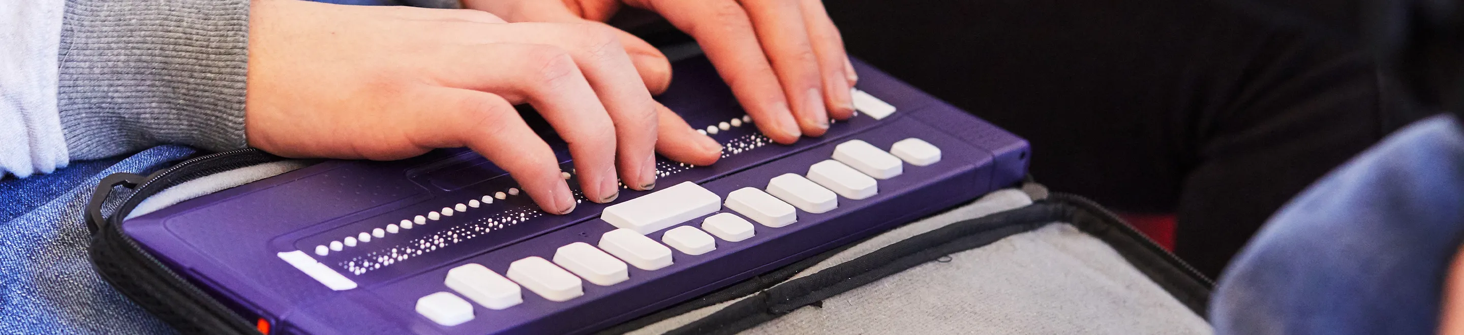 Eine Person nutzt eine Braille-Tastatur.