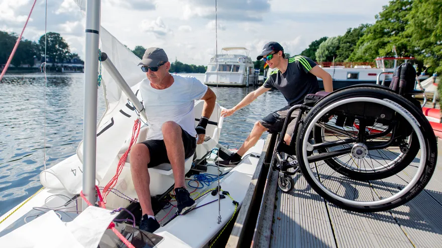 Zwei Rollstuhlfahrer an und in einem Regelboot.