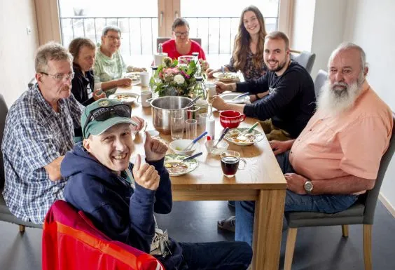 Eine inklusive Wohngemeinschaft: Bewohner*innen mit und ohne Behinderung sitzen an einem Tisch.