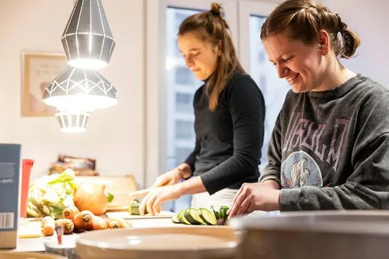 Zwei junge Frauen schnibbeln Gemüse in der Küche