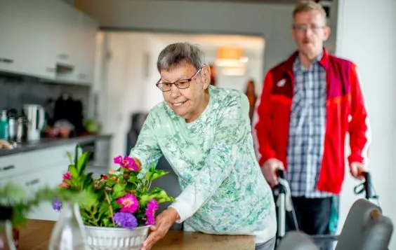 Eine ältere Dame stellt Blumen auf einen Tisch.