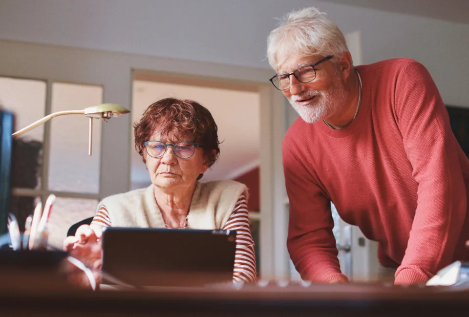 Eine Frau und ein Mann schauen auf einen Laptop.