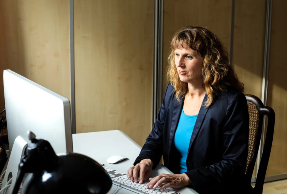 Eine Frau sitzt vor einem Computer-Bildschirm.