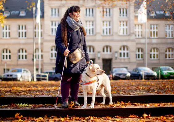 Eine blinde Frau mit einem Blindenführhund.