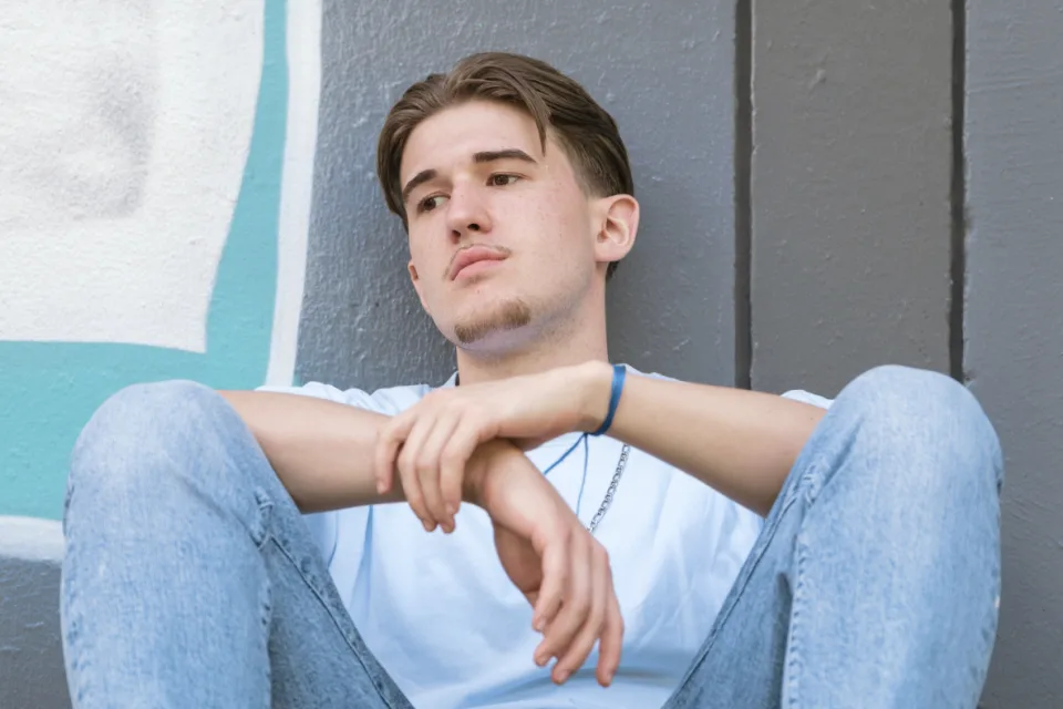Ein junger Mann guckt etwas traurig und gedanken-versunken zur Seite.