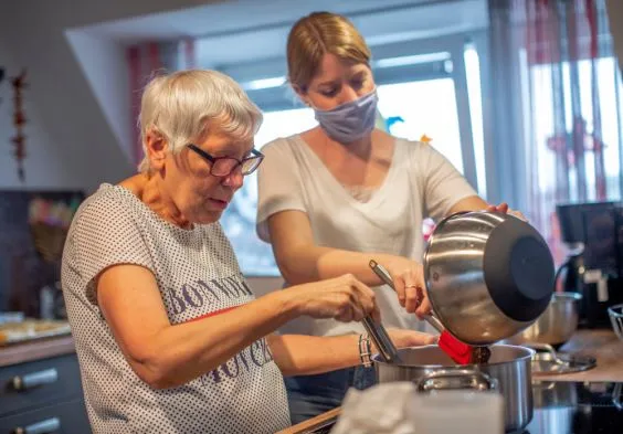 Eine junge Frau hilft einer älteren Frau beim Kochen,