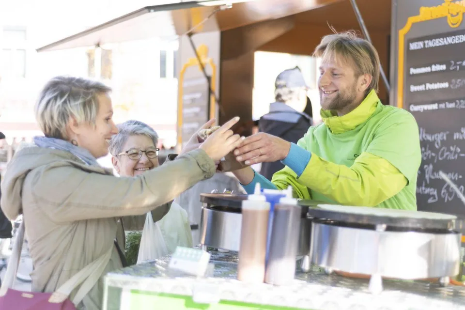Eine Frau kauft etwas an einem Marktstand.