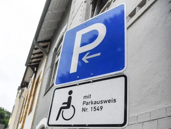 Verkehrsschild "Persönlicher Behindertenparkplatz" mit einem Rollstuhlsymbol und dem Hinweis „Mit Parkausweis Nr. …“.