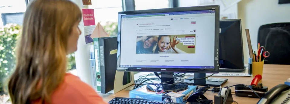 Eine Frau sitzt in einem Büro am Computer.