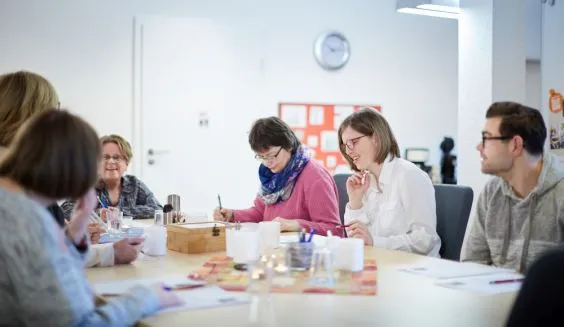 Mehrere Menschen sitzen an einem Tisch und sprechen miteinander.