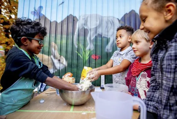 Mehrere Kinder kneten einen Teig.