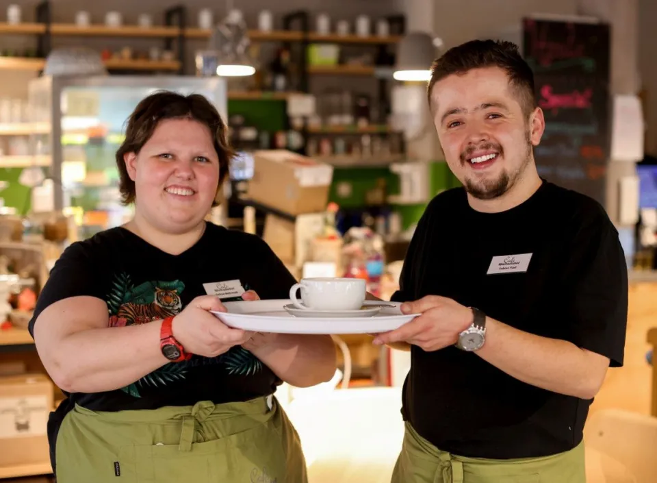 Eine junge Frau und ein junger Mann arbeiten in einem inklusiven Café.
