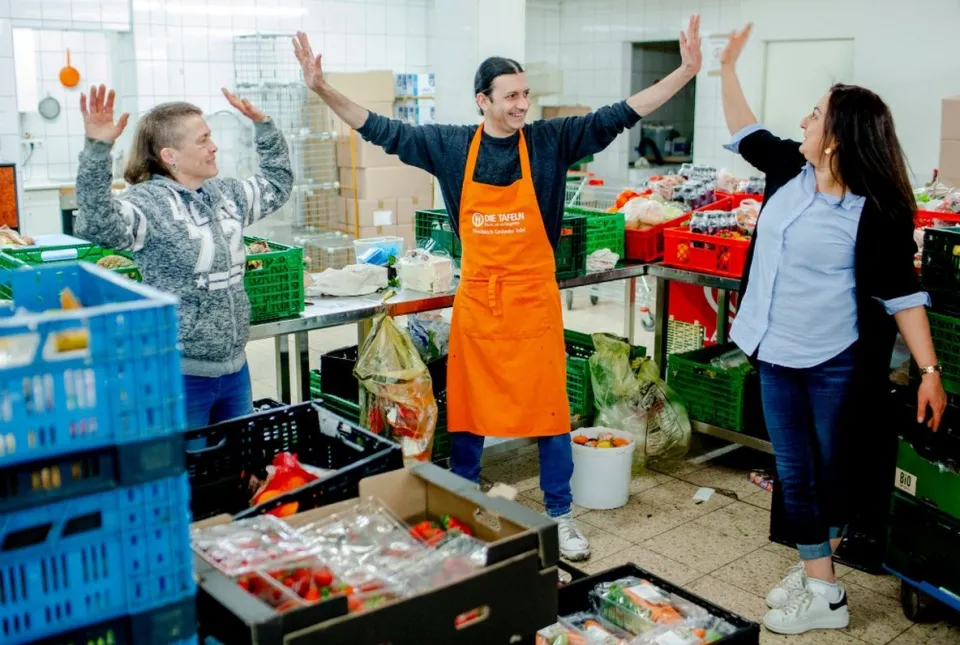 Zwei Frauen und ein Mann, die in einer Verteilstation für Lebensmittel arbeiten.