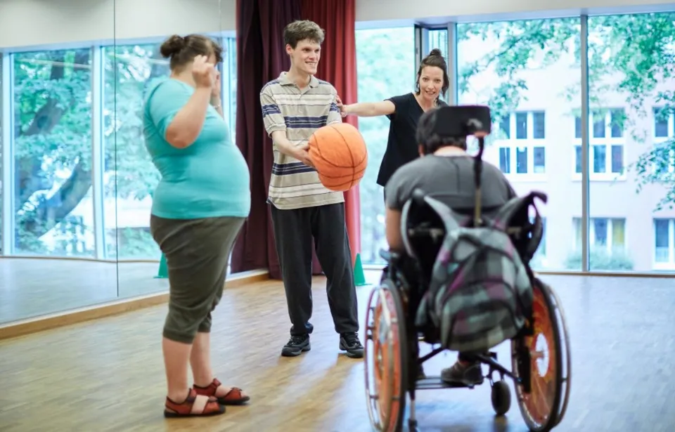 Vier Personen bei einer Bewegungs-Therapie mit einem Ball.