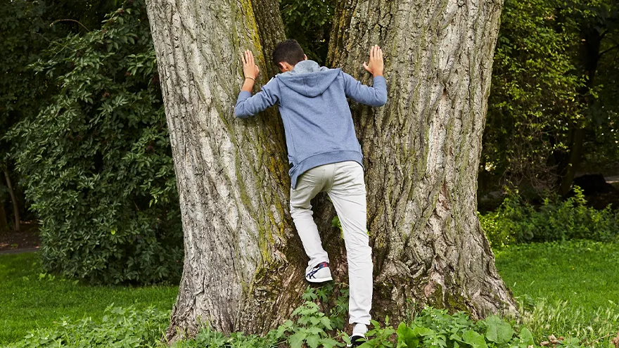Ein junger Mann lehnt sich an einen Baum.