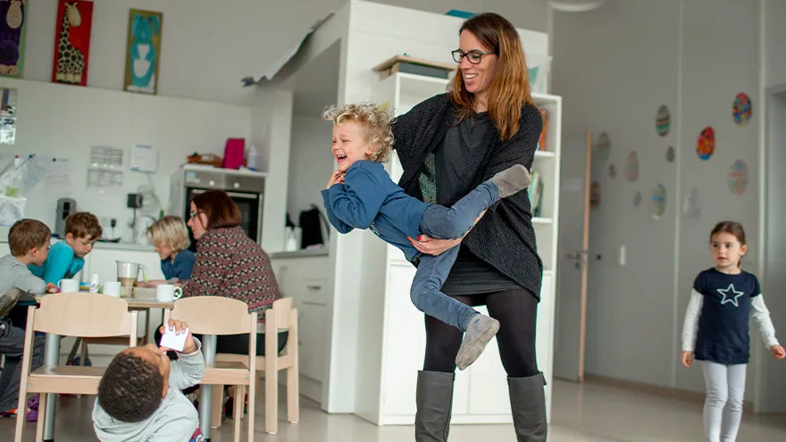 Eine Frau tobt mit einem Kind in einem raum mit anderen Kindern