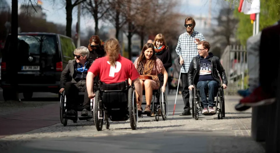 Mehrere Menschen mit Behinderung auf einem Bürgersteig