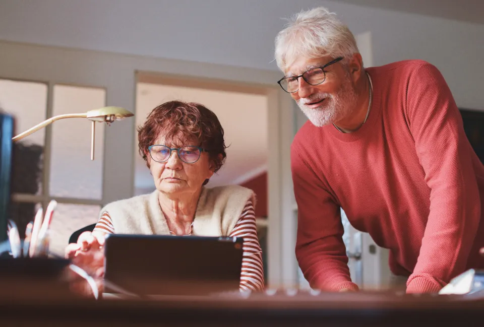 Ein älterer Mann und eine ältere Frau vor einem Laptop