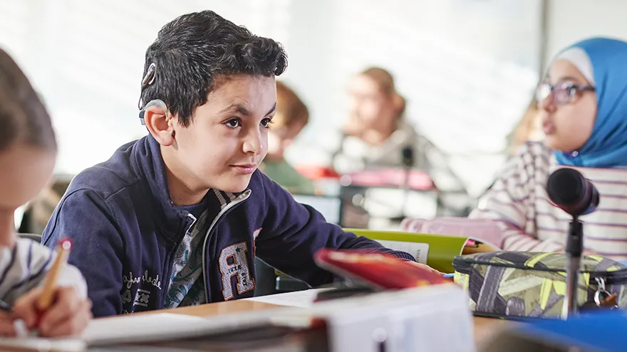 Ein Junge mit Cochlea-Implantat in einer Schulklasse