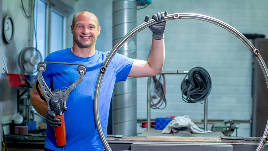 Ein Mann mit blauen T-Shirt steht in einer Werkstatt