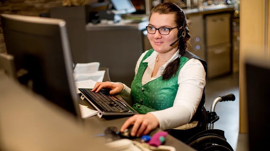 Eine Frau im Rollstuhl arbeitet an einem Computer