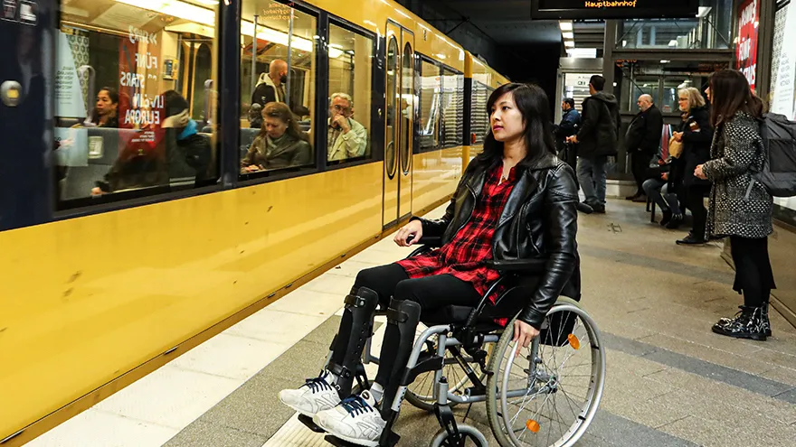 Eine Frau im Rollstuhl vor einer U-Bahn