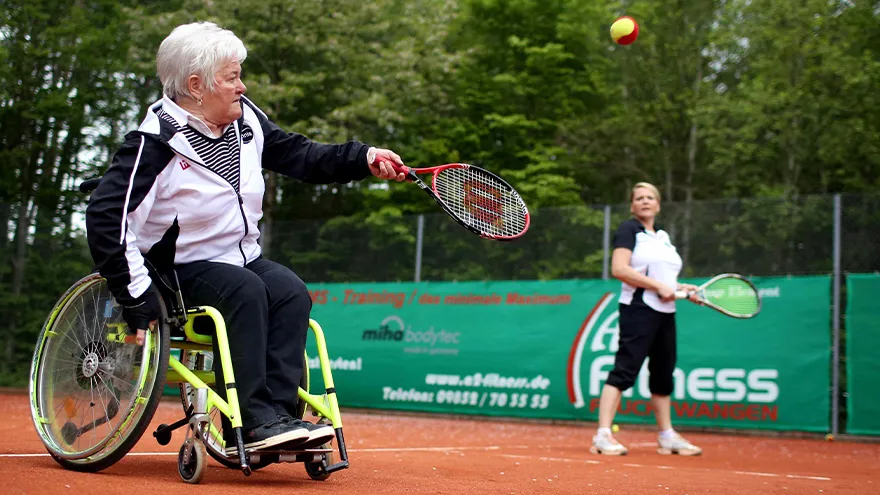 Eine Frau im Rollstuhl spielt Tennis