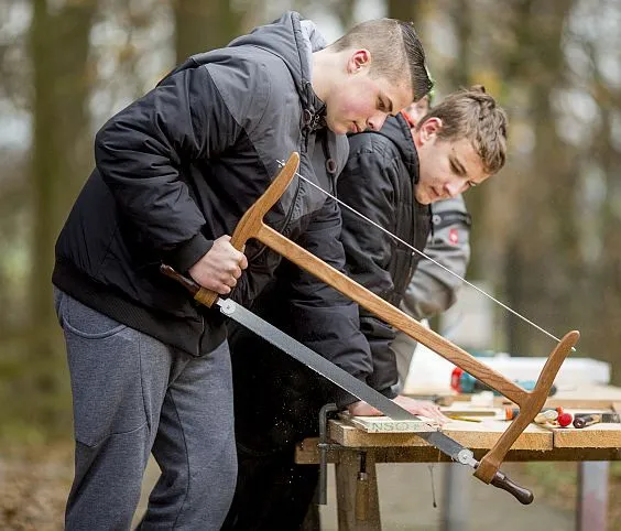 Zwei Jungs sägen ein Brett.