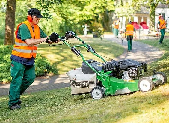 Ein junger Mann mäht einen Rasen.