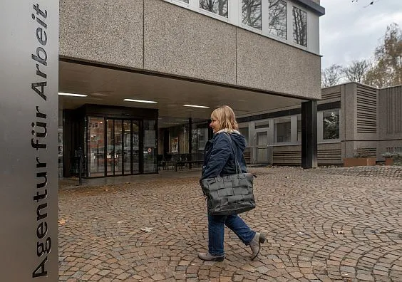 Eine Frau geht auf den Eingang der Agentur für Arbeit zu.