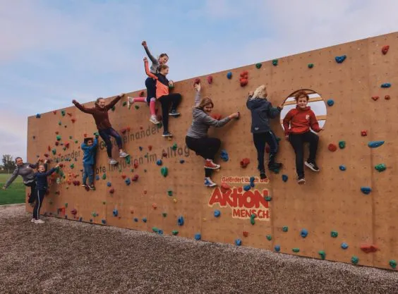 Mehrere Kinder klettern an einer Kletterwand.