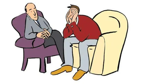 Ein Mann sitzt auf einem Sessel und hält sich die Hände vor das Gesicht. Daneben sitzt ein anderer Mann und hört ihm zu.