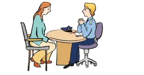 Eine Frau und eine Polozistin sitzen an einem Tisch und sprechen miteinander.