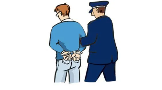 Ein Polizist führt einen Mann in Handschellen ab.