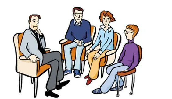 Drei Erwachsene und ein Jugendlicher sitzen auf Stühlen und reden miteinander.