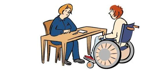 Eine Frau in Arbeitskleidung und eine Frau im Rollstuhl sitzen an einem Tisch und sprechen miteinander.