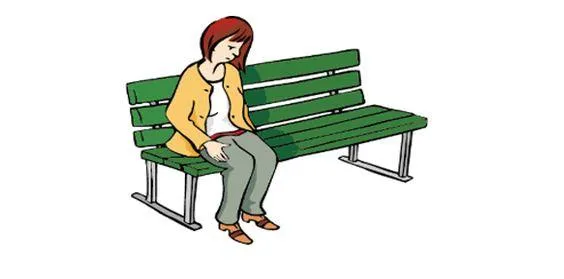 Eine Frau sitzt auf einer Park-Bank und ist traurig.